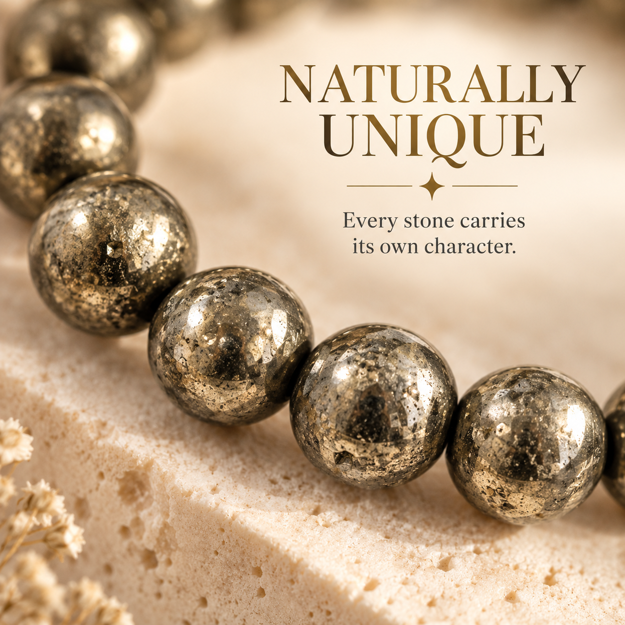 A close-up of metallic gold and silver marbled beads draped across a light beige stone surface, with elegant text reading 'NATURALLY UNIQUE' and 'Every stone carries its own character.'.