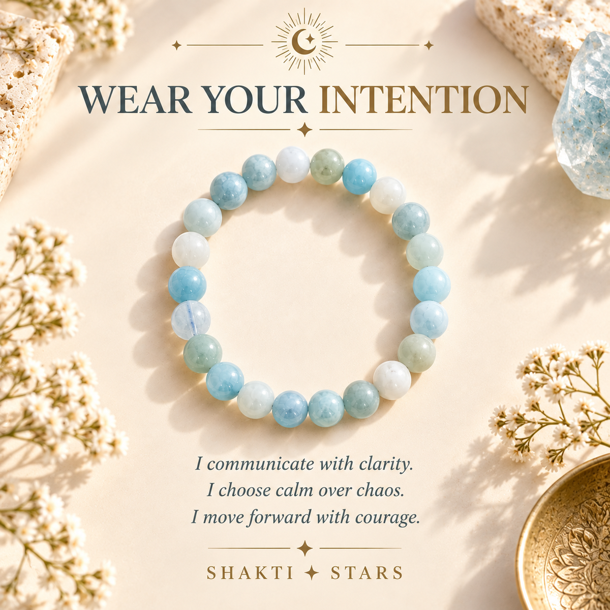 A beaded stretch bracelet made of light blue, mint green, and white round stones, displayed on a warm beige background with decorative dried flowers, crystals, and text reading 'WEAR YOUR INTENTION' and 'SHAKTI STARS'.
