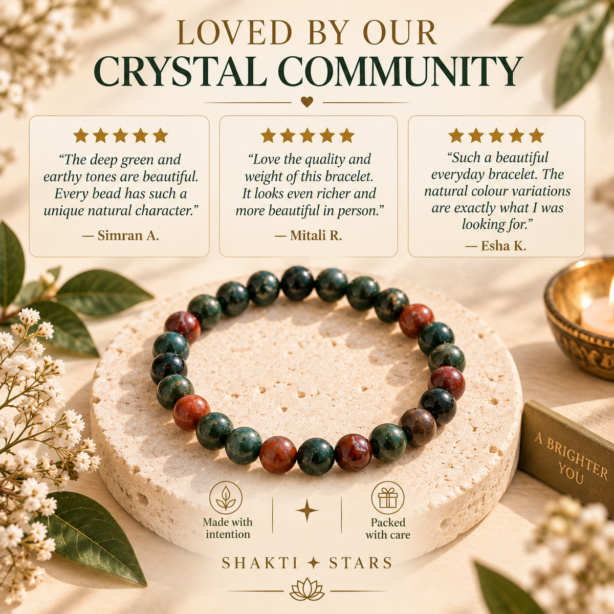 A beaded bracelet made of round marbled beads in deep green, teal, and reddish brown tones, displayed on a beige stone pedestal. The image is a promotional graphic with the text 'LOVED BY OUR CRYSTAL COMMUNITY' and three customer review cards, branded with 'SHAKTI STARS'.